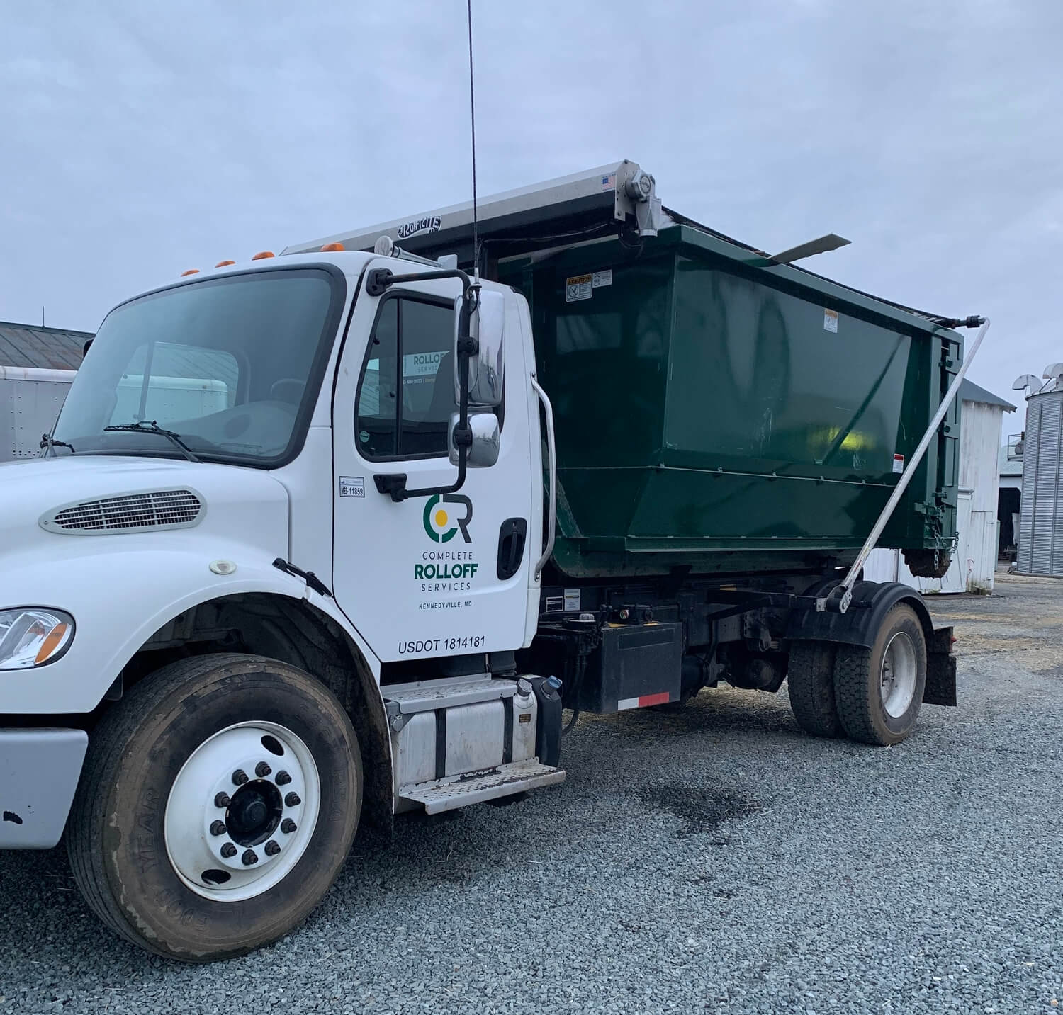 A Complete Rolloff Services truck with a rolloff container before delivery